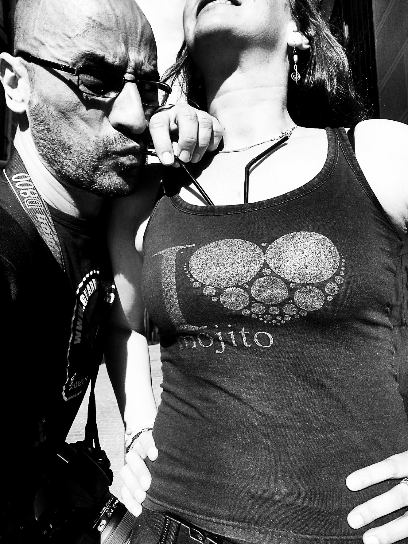 Close-up of a man in glasses biting the lanyard of his accreditation beside a woman in an "I ♥ mojito" T-shirt.