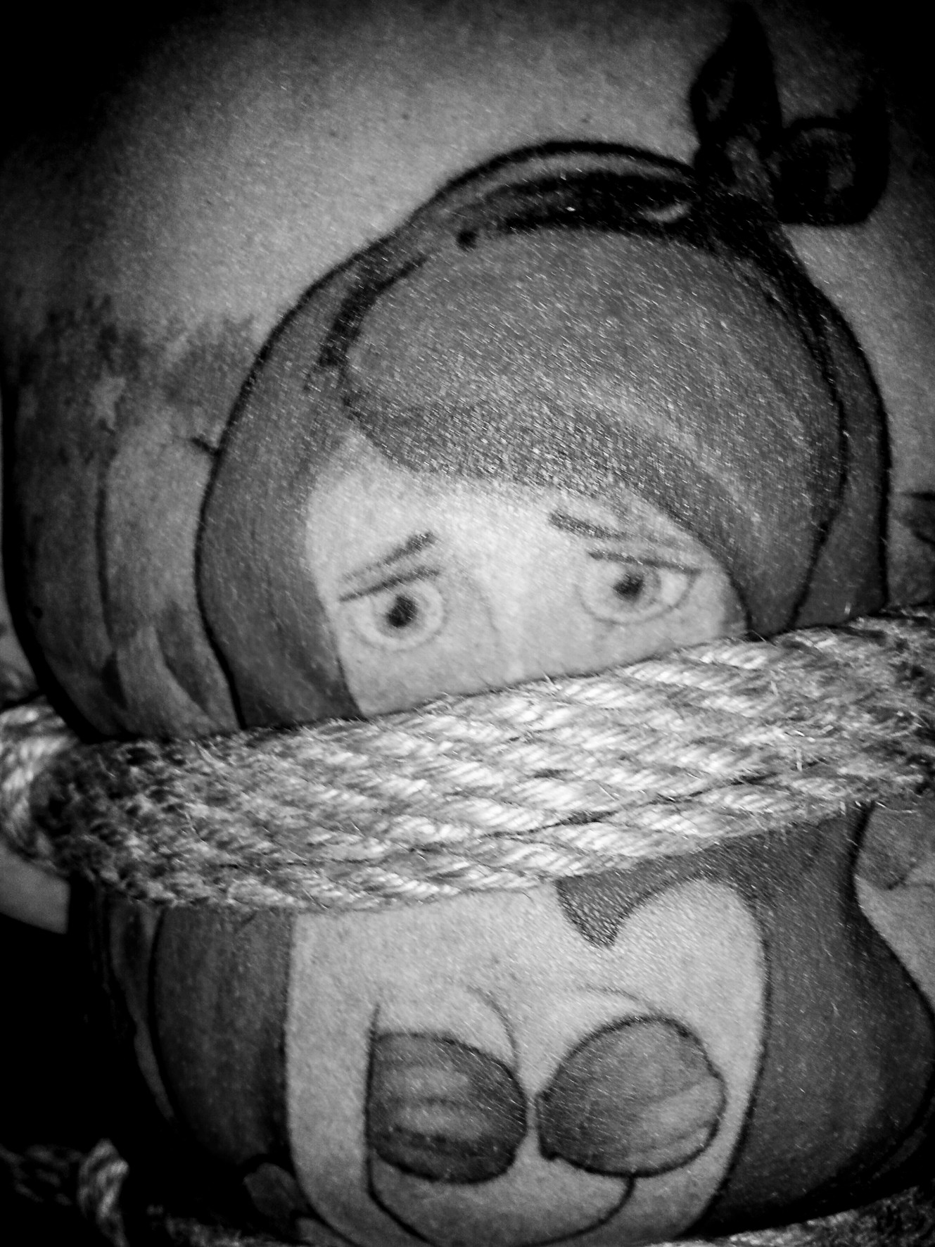 A rag doll tied with a thick rope around its neck, eyes looking upward.