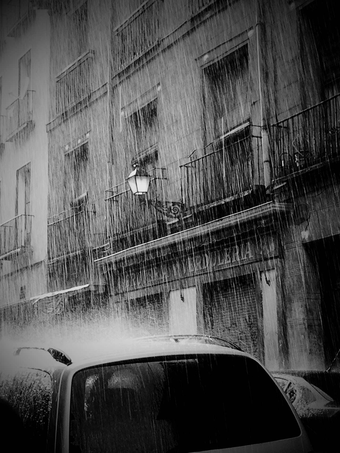 A rain-soaked street, with cars and buildings blurred by the downpour.
