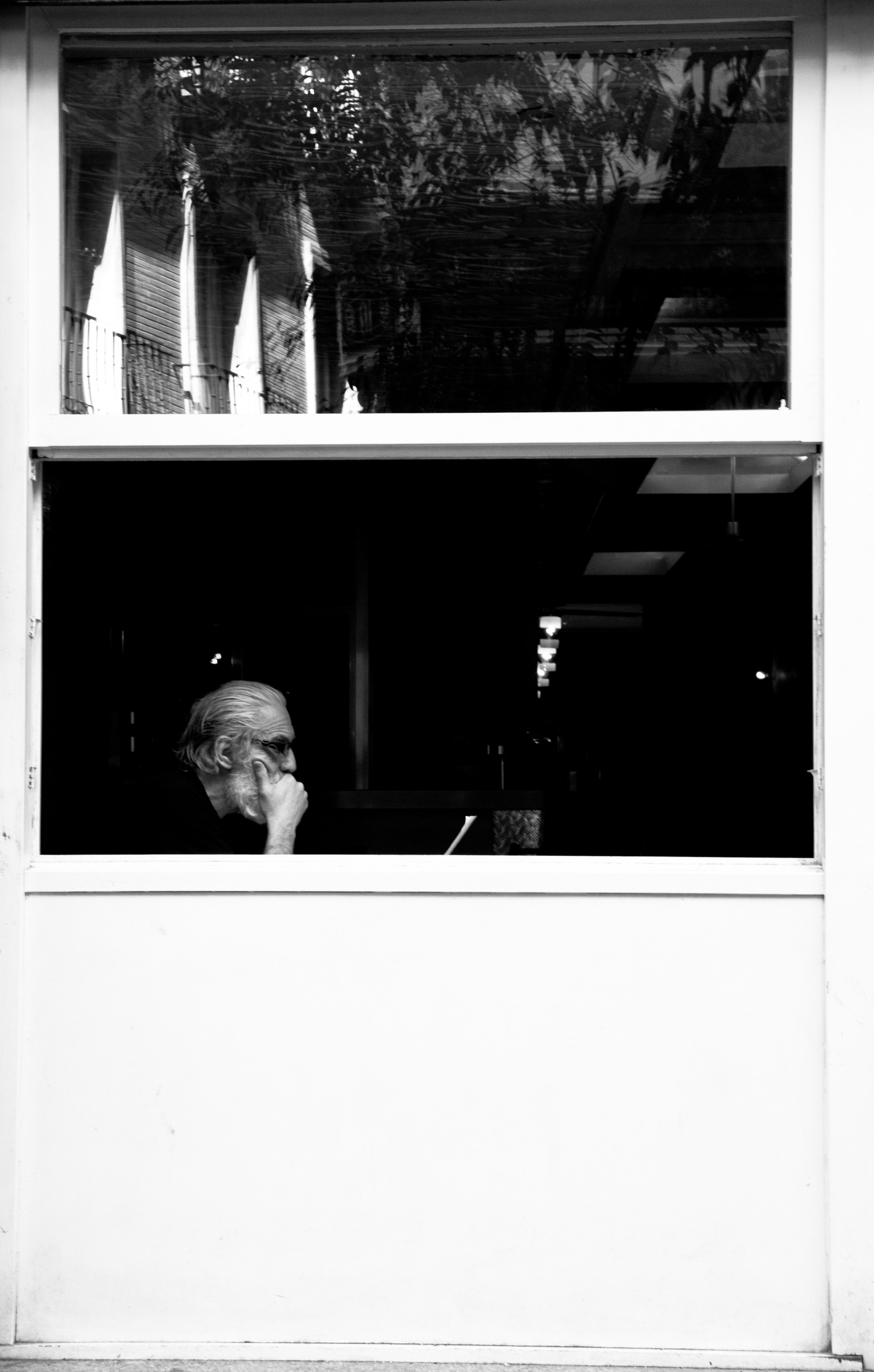 A man with his hand on his chin at the window of a white booth.