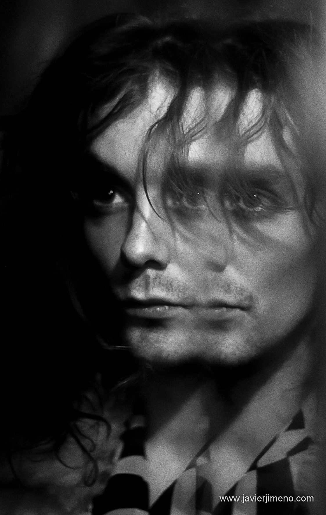 Close-up portrait of a young man with hair falling over his face and an intense gaze.