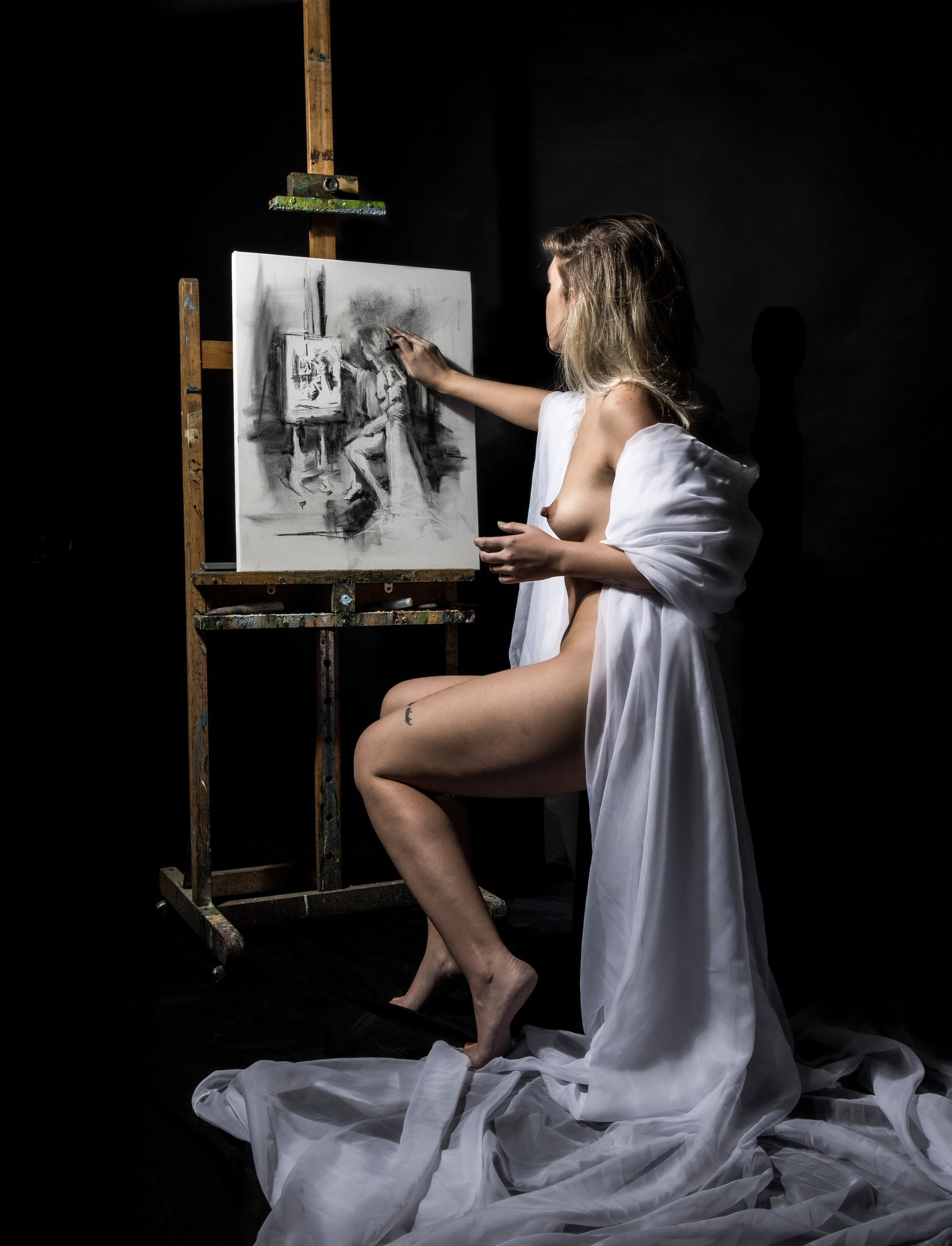 "La pintora". A nude woman drawing at an easel, wrapped in white tulle.