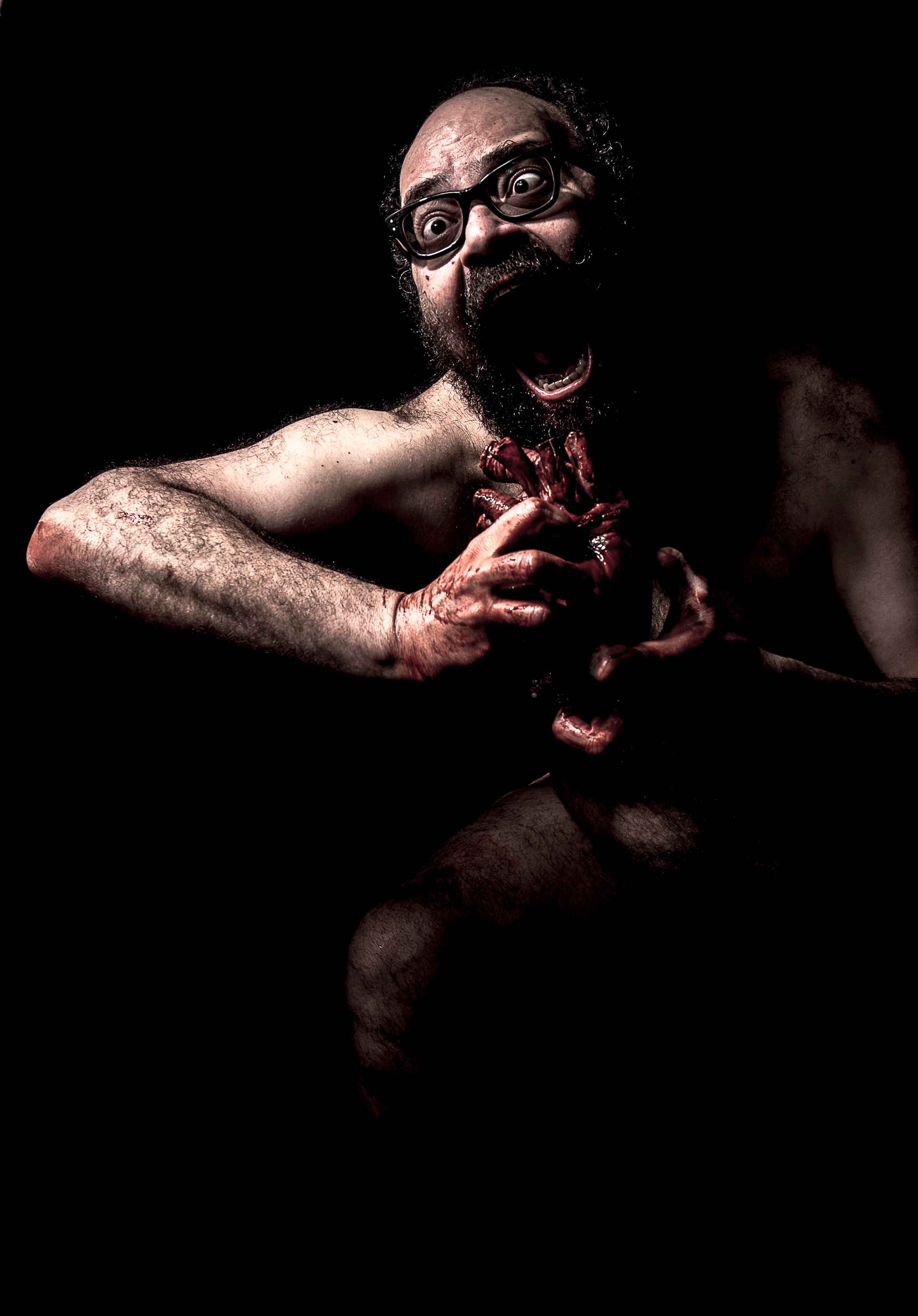 "Cronos". A nude bespectacled man, bloodied, screaming with raised hands.